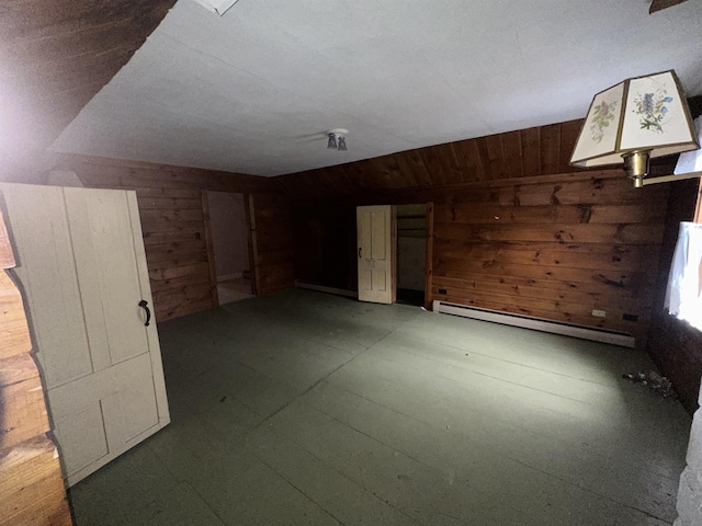 spare room with vaulted ceiling, wood walls, and a baseboard radiator