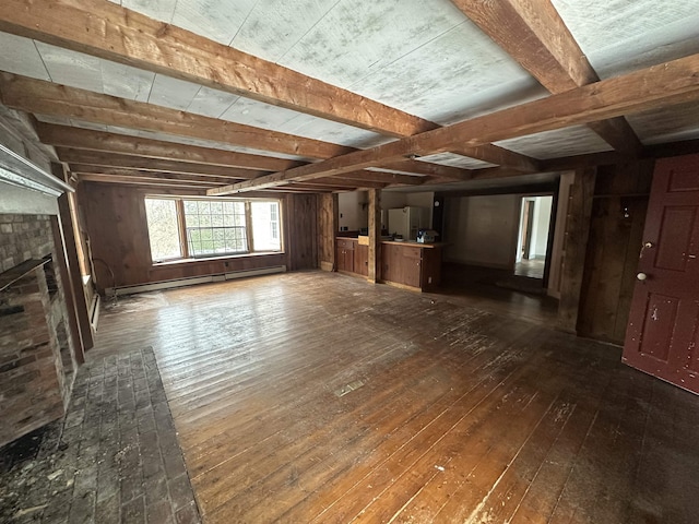 unfurnished living room featuring a baseboard heating unit, wood walls, hardwood / wood-style floors, beam ceiling, and a fireplace