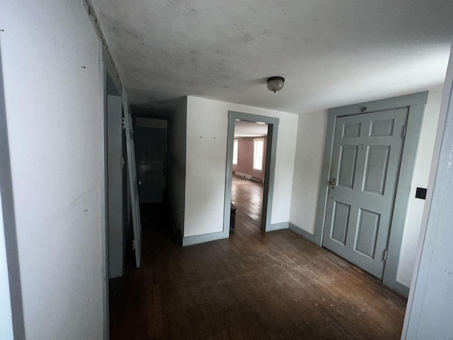 corridor featuring dark wood-type flooring and baseboards