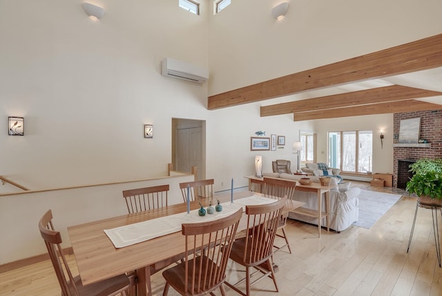 dining room with a brick fireplace, beamed ceiling, light wood-style flooring, a towering ceiling, and a wall mounted AC