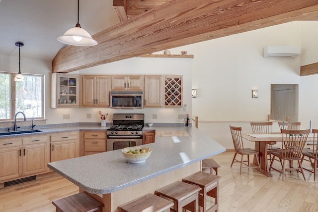 kitchen with a kitchen bar, light brown cabinetry, a wall mounted AC, a sink, and stainless steel appliances