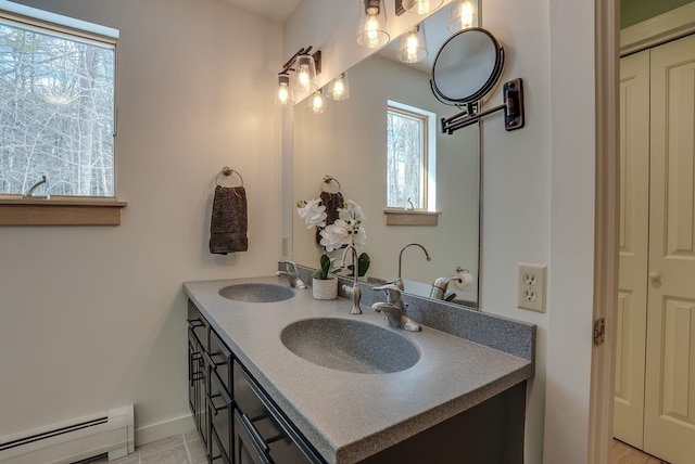 bathroom featuring double vanity, baseboard heating, baseboards, and a sink