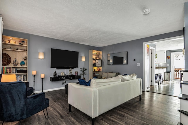 living room featuring baseboards, dark wood-type flooring, and a textured ceiling