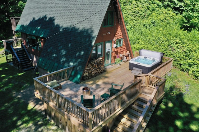 wooden terrace with a covered hot tub, stairway, and an outdoor fire pit