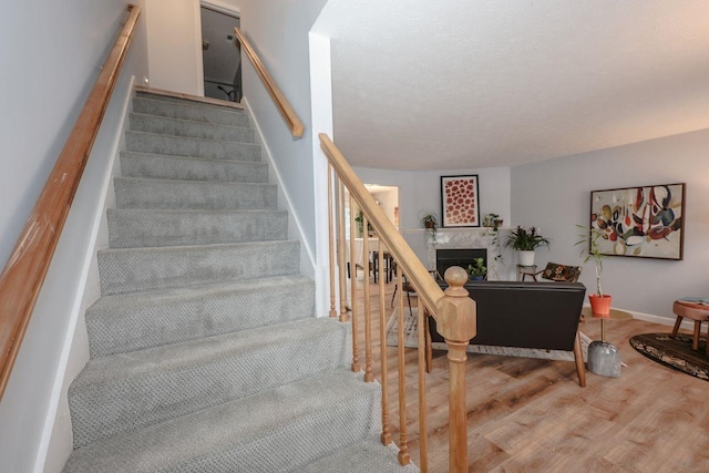 stairway with a fireplace, baseboards, and wood finished floors