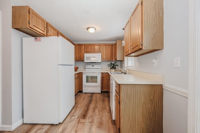 kitchen with light wood-style flooring, a sink, white appliances, light countertops, and baseboards