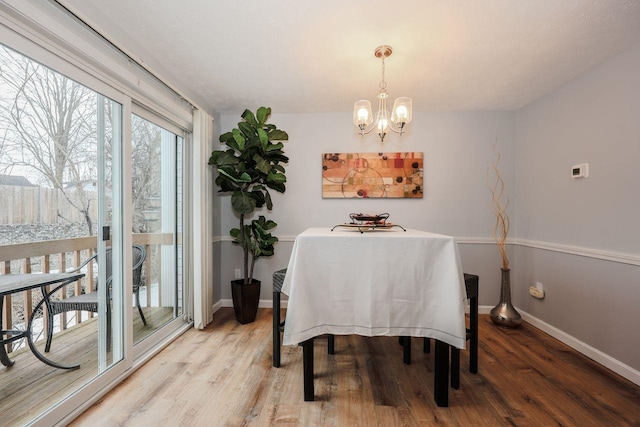 dining room featuring baseboards, an inviting chandelier, and light wood finished floors