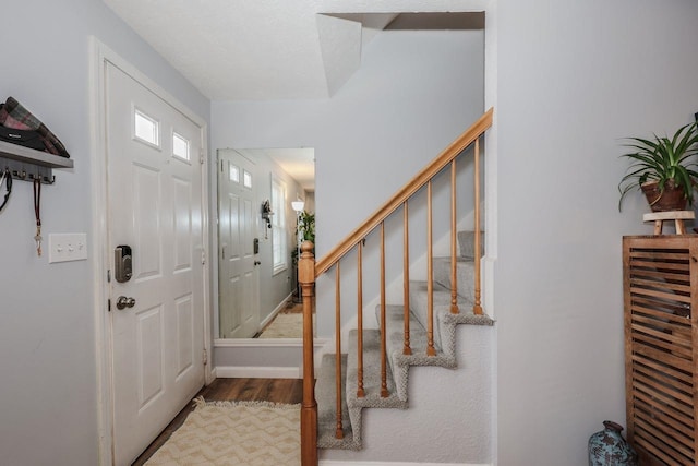 foyer entrance with stairs, baseboards, and wood finished floors