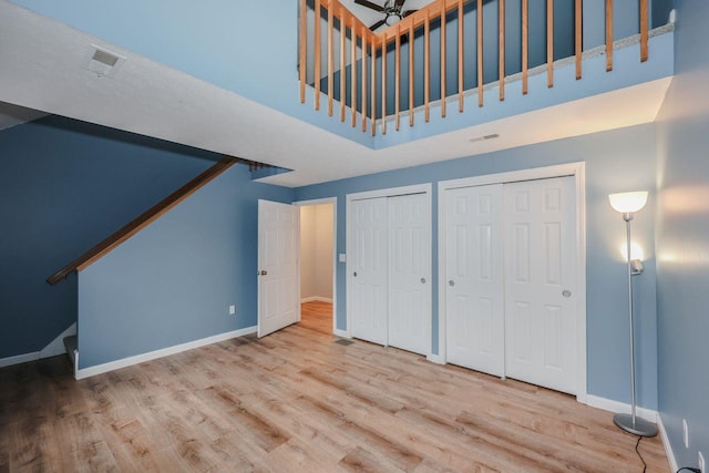 interior space with visible vents, baseboards, multiple closets, and wood finished floors