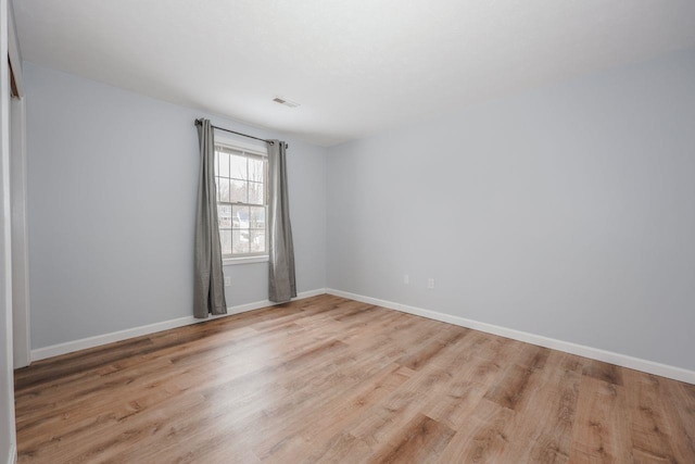 spare room featuring wood finished floors, visible vents, and baseboards