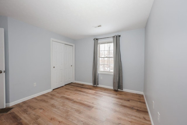 unfurnished room with light wood finished floors, visible vents, and baseboards