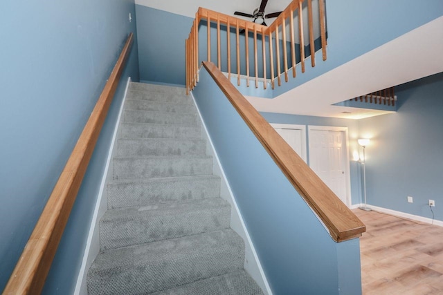 staircase featuring baseboards, ceiling fan, and wood finished floors