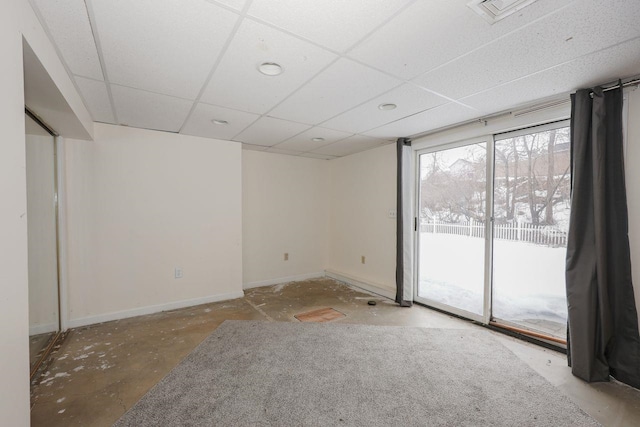 spare room with baseboards, a paneled ceiling, visible vents, and unfinished concrete floors