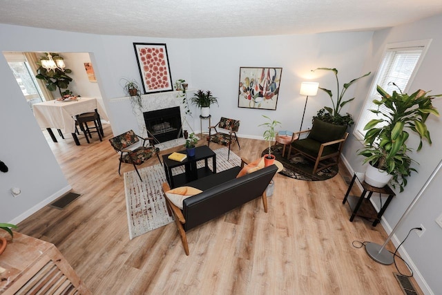 living area featuring a premium fireplace, light wood-style floors, visible vents, and a textured ceiling