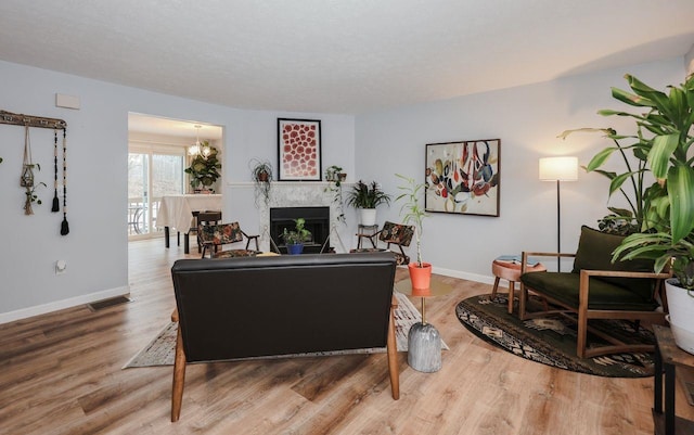 living room with a fireplace, visible vents, wood finished floors, and baseboards