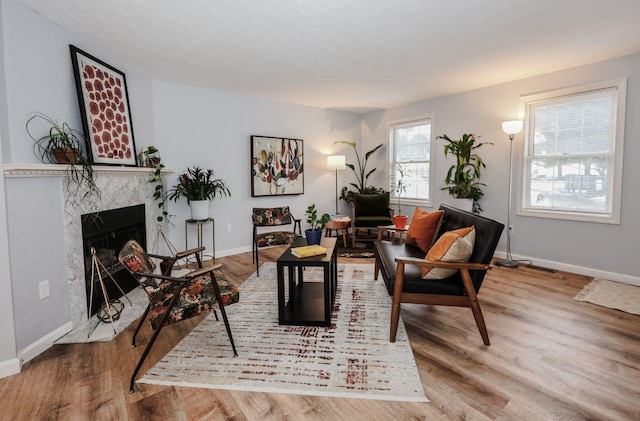 living room with a premium fireplace, baseboards, and wood finished floors