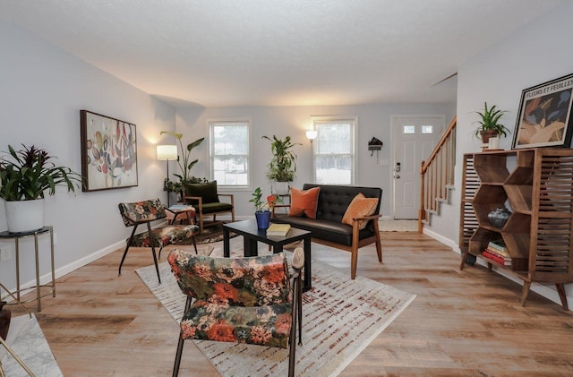 living area with stairway, light wood-type flooring, and baseboards