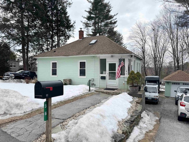 view of front of house featuring an outbuilding, a chimney, and roof with shingles