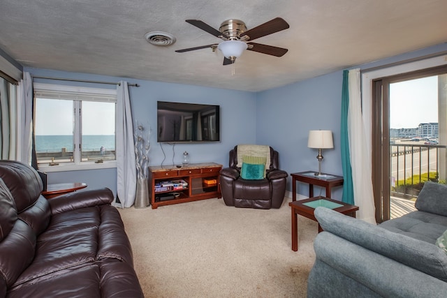 carpeted living room featuring a ceiling fan, visible vents, and a textured ceiling