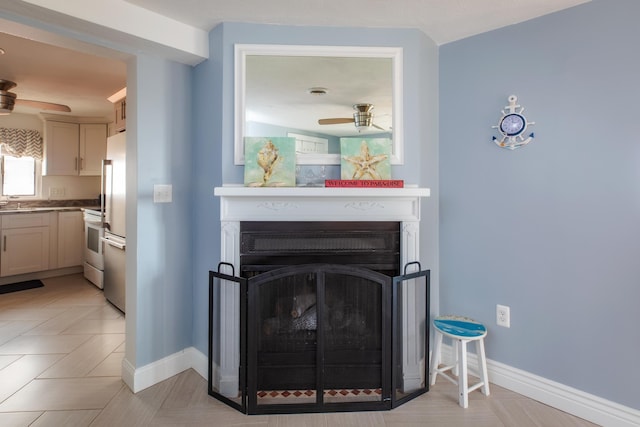 room details featuring a fireplace, baseboards, freestanding refrigerator, and a ceiling fan