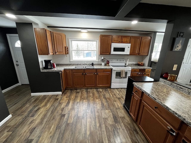 kitchen featuring dark wood finished floors, white appliances, brown cabinetry, and a sink