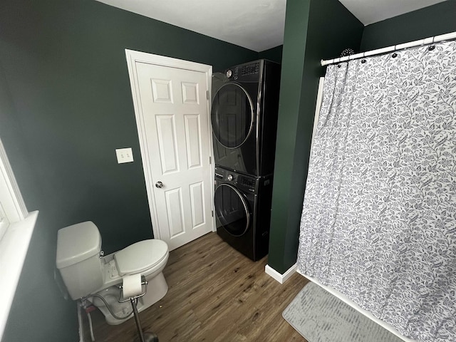 full bathroom with stacked washer / drying machine, toilet, wood finished floors, and a shower with curtain