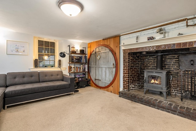 carpeted living area with a wood stove and wood walls