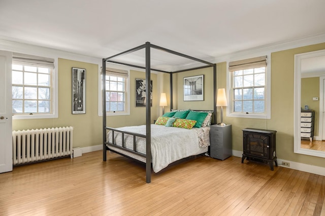 bedroom featuring multiple windows, radiator, and light wood-style flooring