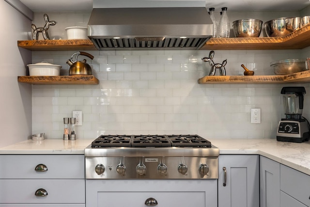 kitchen with open shelves, light stone counters, backsplash, exhaust hood, and stainless steel gas cooktop