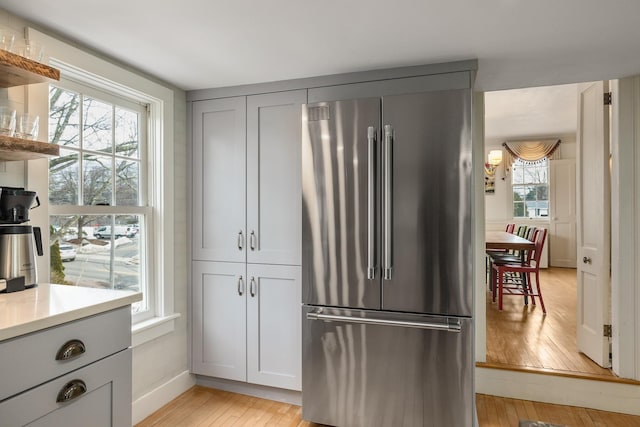 kitchen featuring gray cabinets, light wood-style floors, high quality fridge, light countertops, and baseboards