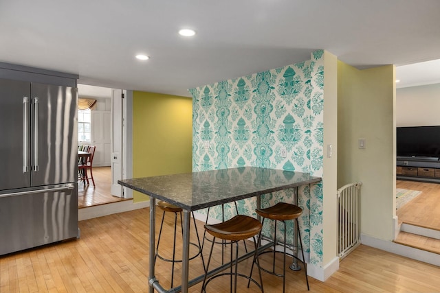 kitchen with wood finished floors, baseboards, recessed lighting, high end fridge, and dark countertops