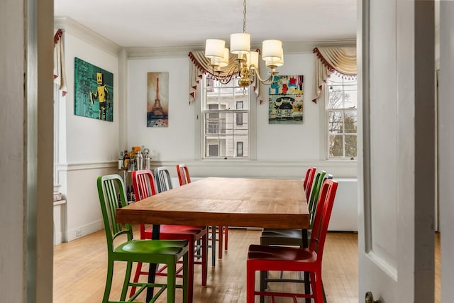 dining space featuring an inviting chandelier, wood finished floors, and crown molding