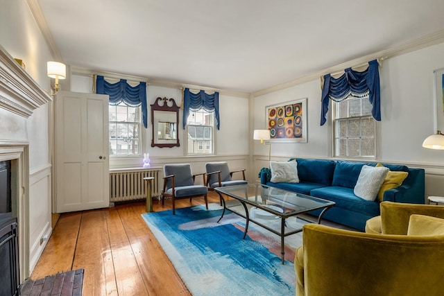 living area with light wood-type flooring, radiator heating unit, wainscoting, a fireplace, and crown molding