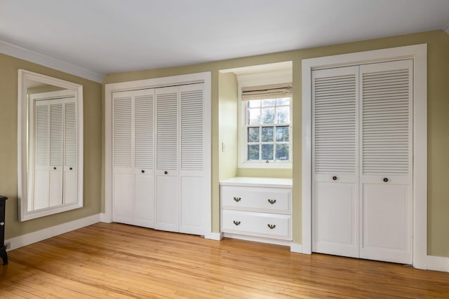 unfurnished bedroom with baseboards, light wood-style floors, and multiple closets