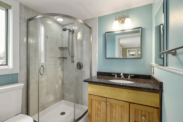 bathroom with vanity, a shower stall, and toilet