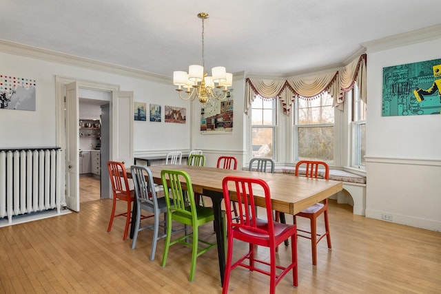 dining space featuring an inviting chandelier, radiator, light wood-type flooring, and ornamental molding