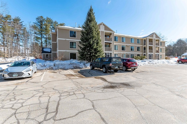 snow covered property featuring uncovered parking