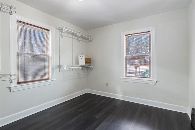 unfurnished room with baseboards and dark wood-style flooring