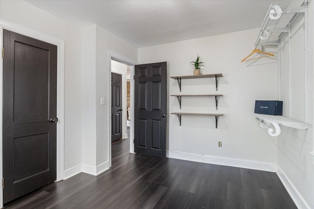 spare room with baseboards and dark wood-style flooring