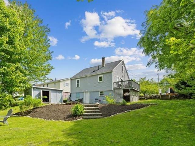 back of property featuring a yard, an outbuilding, and a wooden deck