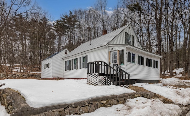 view of front of house with metal roof and a chimney