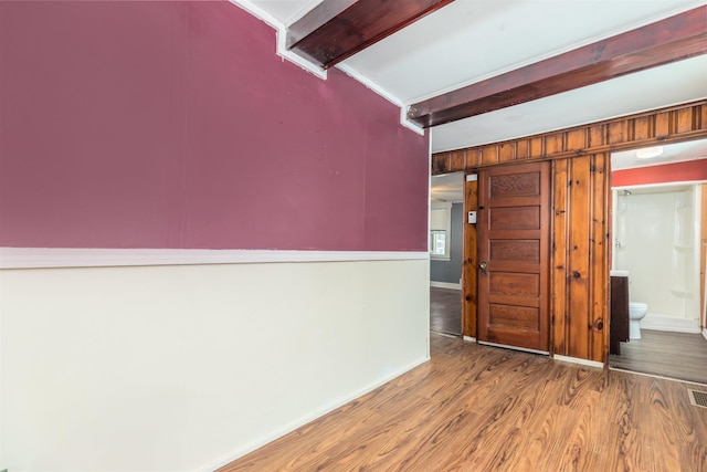 spare room with beamed ceiling, wooden walls, wood finished floors, and baseboards