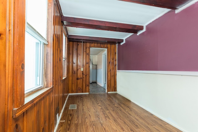 hall with beamed ceiling, visible vents, wooden walls, and wood finished floors