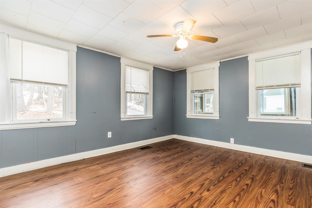 empty room featuring visible vents, baseboards, dark wood-type flooring, and a ceiling fan