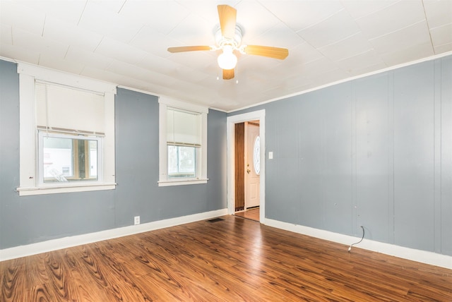 unfurnished room featuring visible vents, ornamental molding, a ceiling fan, wood finished floors, and baseboards