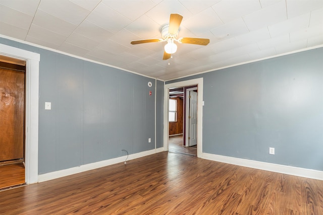 spare room with crown molding, wood finished floors, baseboards, and ceiling fan