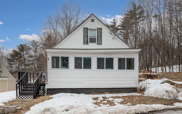 snow covered property featuring a wooden deck and metal roof