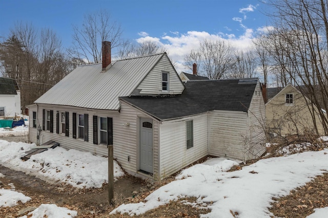 view of snow covered exterior with a chimney and metal roof