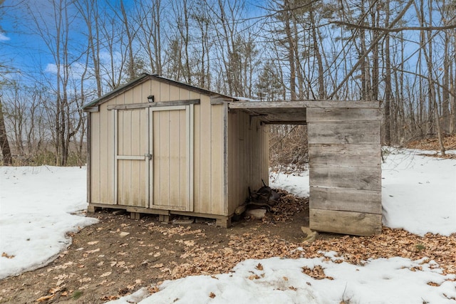 snow covered structure with an outbuilding and a storage shed