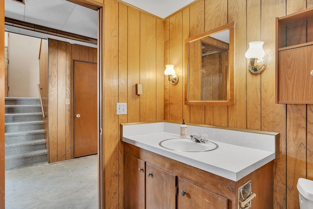 bathroom featuring vanity, toilet, concrete flooring, and wood walls